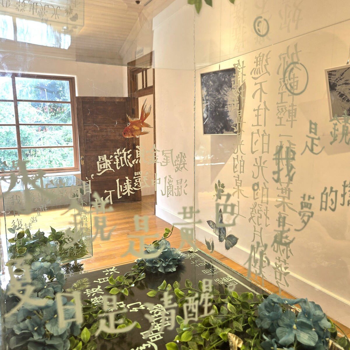 〈光閘〉懸掛著綠色壓克力方塊與藍染布，彷彿夏日的明亮閃光，青翠的植物則是躍動的生命在狂放。(另開新視窗/jpg檔)圖片