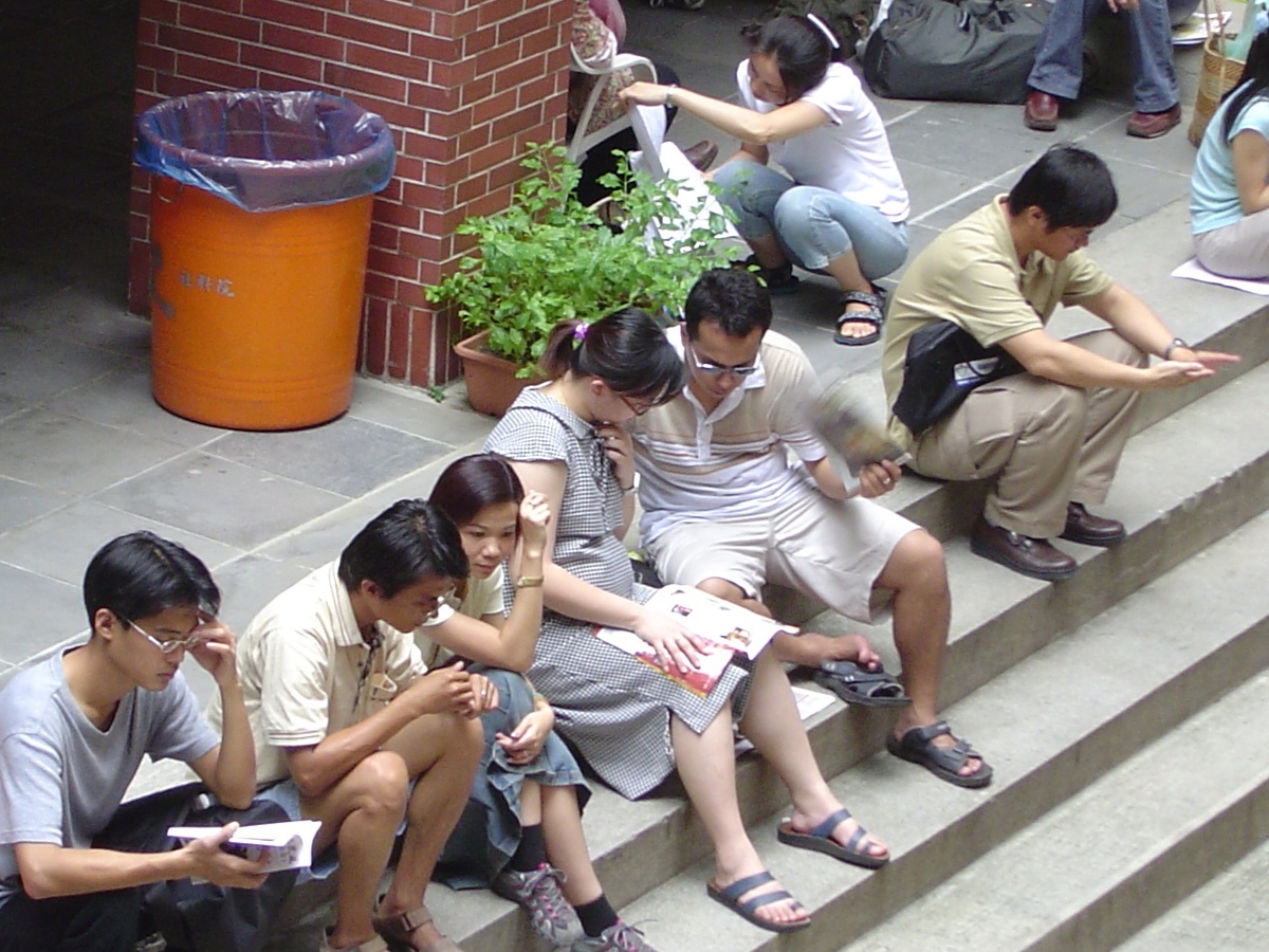 一位孕婦考生趁休息時候再多K點書,貼心的先生在一旁忙著為她搧風解熱.(另開新視窗/jpg檔)圖片