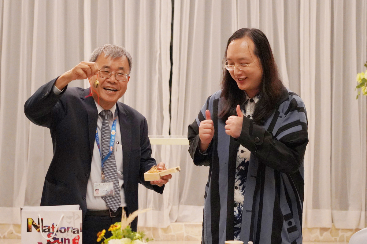 國立中山大學邀請行政院政務委員唐鳳(右)蒞校分享「台灣社會創新發展趨勢」,校長鄭英耀(左)致贈「牛鈴」紀念品。圖/西灣學院提供